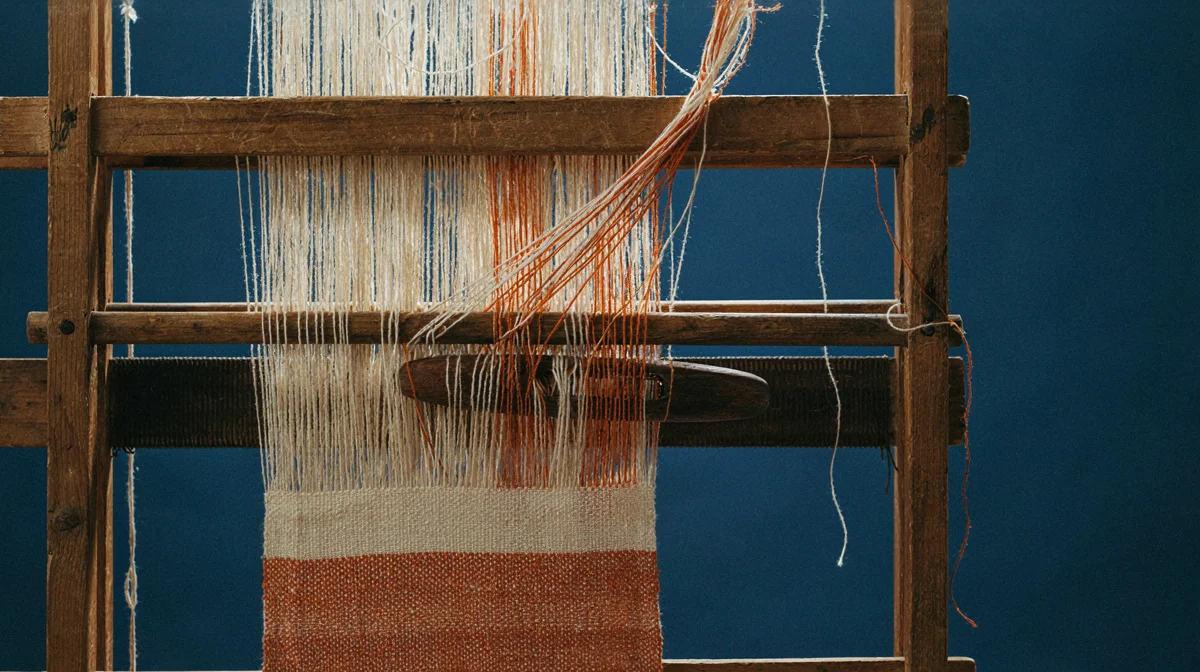 A weaving loom with many threads coming together into one piece of cloth, representing a large language model trained on huge amounts of text