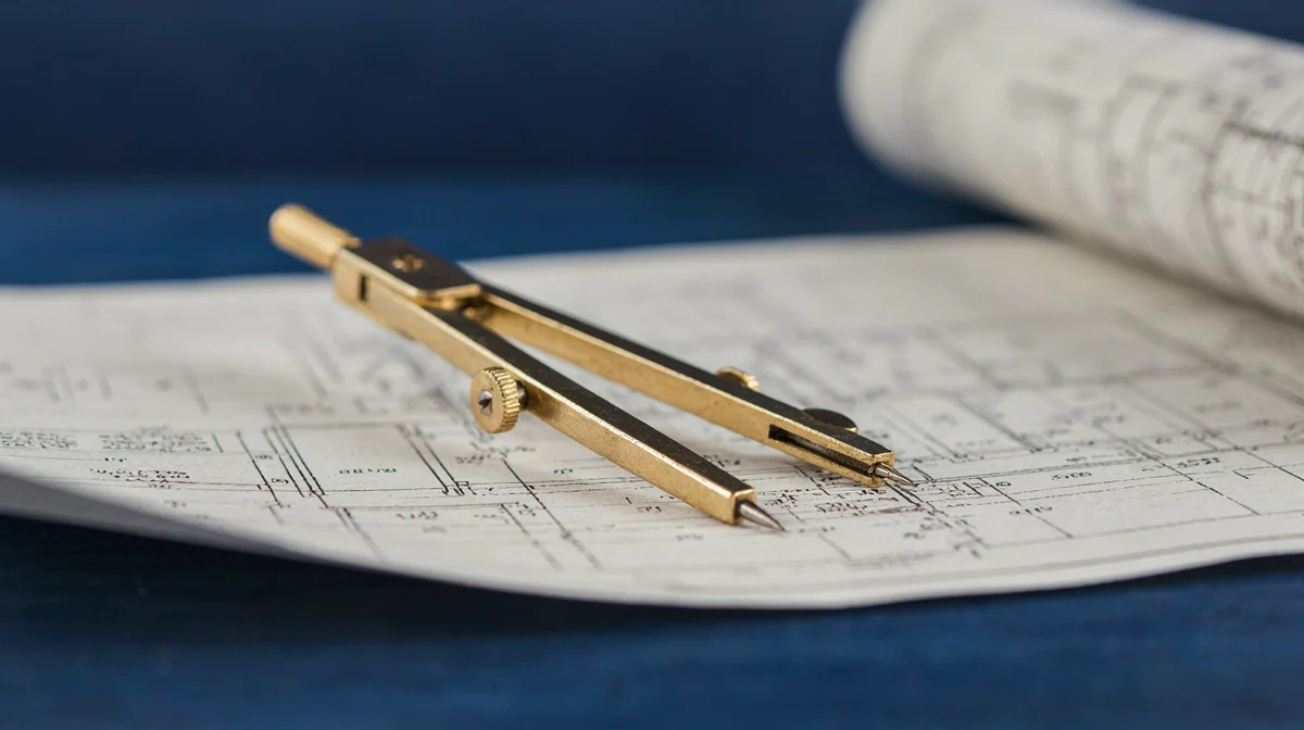 A brass drafting compass resting on a rolled blueprint, representing the technical lead who scopes what is realistically achievable