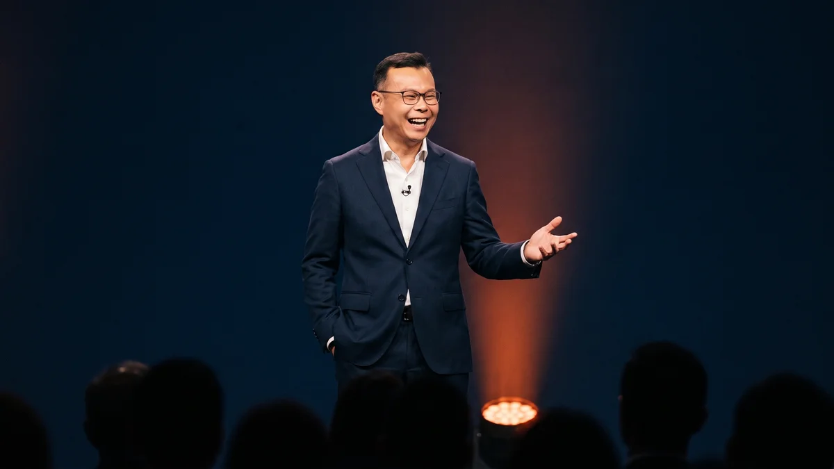 A speaker laughing warmly while addressing an audience on stage