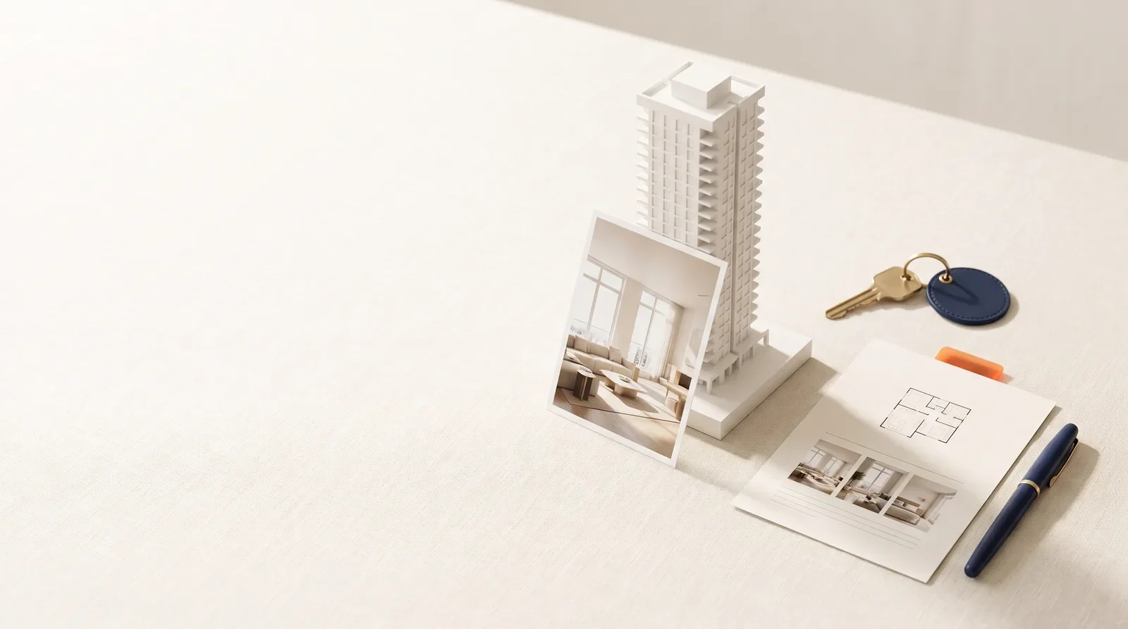 Still life of a white tower model, an interior photograph, a floor plan sheet, a key and a pen