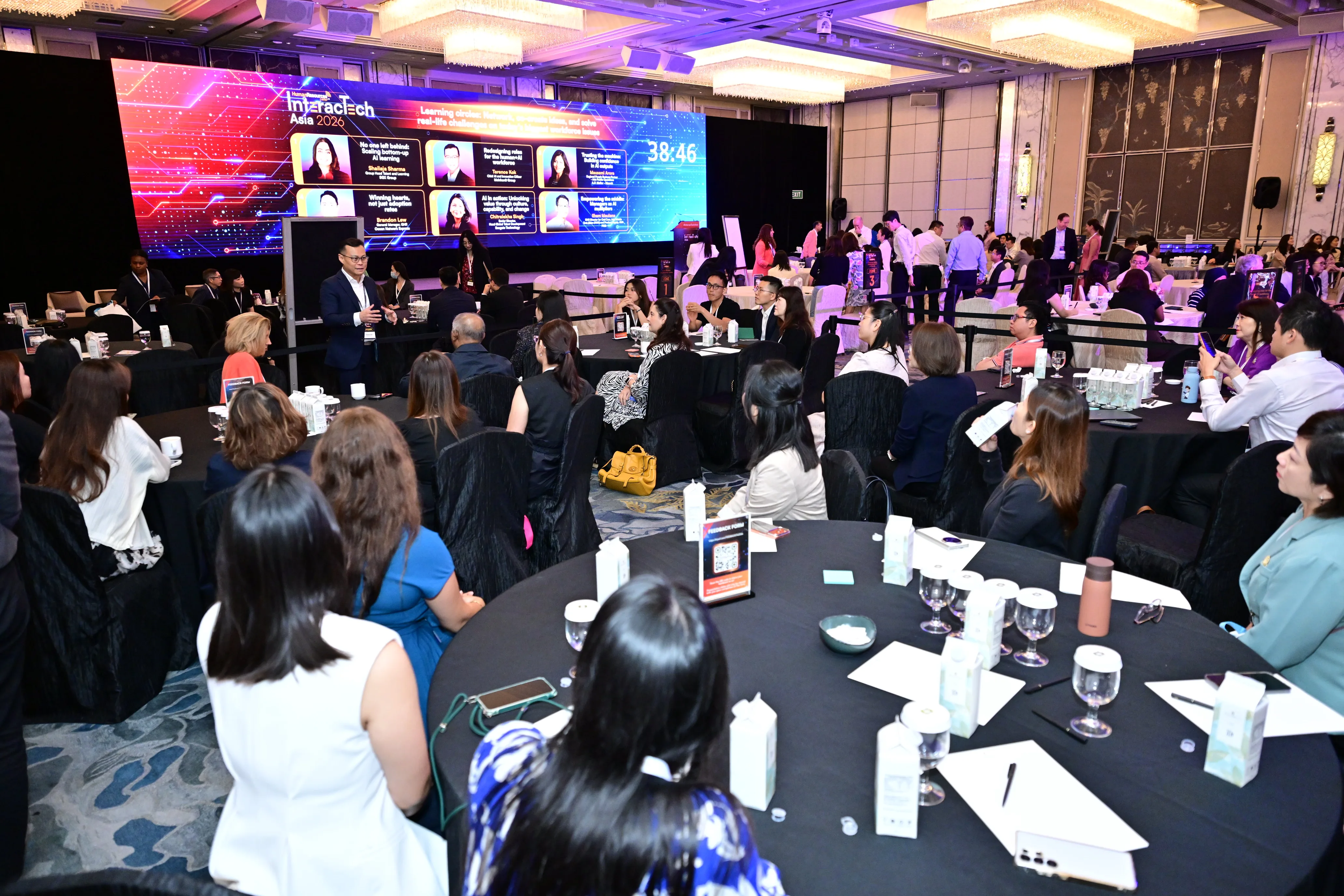 Terence Kok moderating AI in HR session at InteracTech Asia 2026, full ballroom audience with event branding on screen